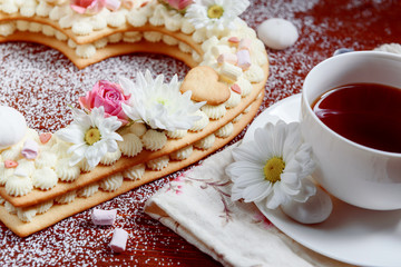 Valentine's Day heart-shaped cake with flowers as decoration. The concept of a gift to a loved one on a holiday.