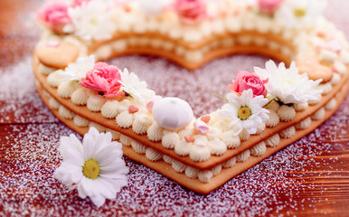 Fototapeta na wymiar Valentine's Day heart-shaped cake with flowers as decoration. The concept of a gift to a loved one on a holiday.