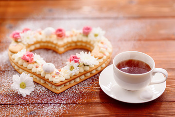 Valentine's Day heart-shaped cake with flowers as decoration. The concept of a gift to a loved one on a holiday.