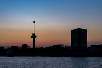 Fototapeta na wymiar Silhouette of the skyline of Rotterdam at sunset. The mast is an observation tower called 