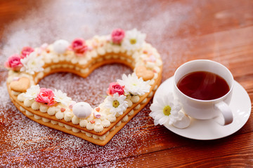 Valentine's Day heart-shaped cake with flowers as decoration. The concept of a gift to a loved one on a holiday.