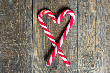 candy canes in heart shape on wooden background