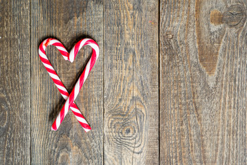 candy canes in heart shape on wooden background