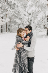  couple in love walking in the snowy forest, hugging, kissing and enjoying