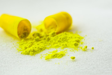 Macro view from yellow open capsule medicine isolated on white background.