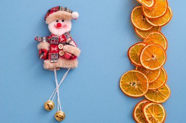 Fototapeta na wymiar Dried slices oranges citrus fruit and funny snowman on light blue background. Homemade natural aroma decor. Concept of holiday. Marry Christmas. Close up, flat lay, top view