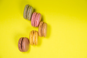Colorful french macarons isolated on yellow background. Pastel colors - Imagen