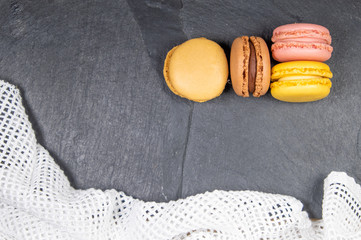 Assorted colorful french macarons isolated on chalkboard stone background with dishcloth. Pastel colors - Image