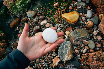White stone in hand on a background of stones