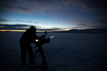 Silhouette of people who filming sunset in desert of Siberia.