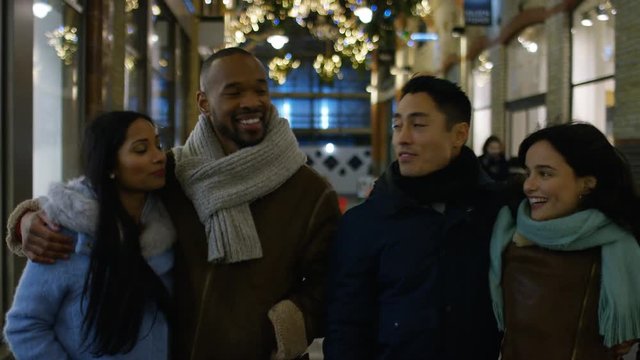 Happy group of diverse young couples walking the street at Christmas, in slow motion