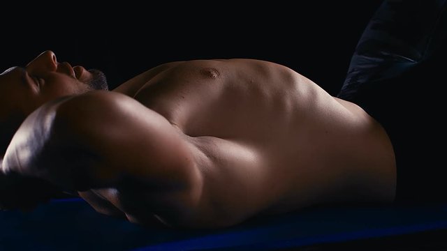 Handsome strong bodybuilder athletic man doing abs workout situps on the floor on black background bodybuilding concept, 4k