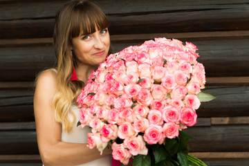 young pretty with a light and long hair girl smiling pleasantly holds a large bouquet of white and...