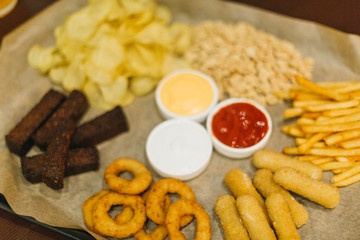Lager beer and snacks on wooden table. Nuts, chips, peanut, toast, crackers. Appetizer fast food. Craft beer. Beerboard. Tomato, cheese, garlic sauce.