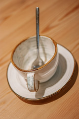 Empty ceramic mug on wooden table with spoon inside