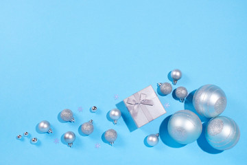 Gift box and Christmas baubles on blue background.