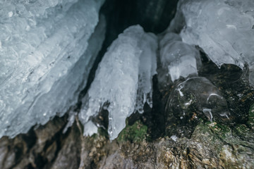 Winter Baikal. Olkhon Island. Ice grotto. Thick blue ice and icicles on the coastal rocks of Olkhon Island in winter. Natural cold background. The winter the lake and the surrounding area becomes ice.