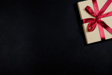 Gift box with red bow on black background.