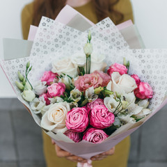 Colorful bouquet of different fresh flowers in the hands of a florist woman. Rustic flower background. Craft bouquet of flowers.
