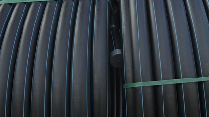 Warehouse of finished plastic pipes industrial outdoors storage site. Manufacture of plastic water pipes factory. Process of making plastic tubes on the machine tool with the use of water and air