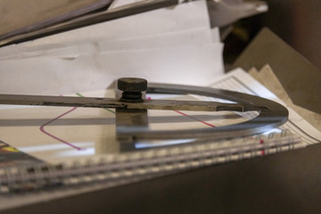 Close up a part of the precision measurement tool laying on a table with plans, calculations and measurements