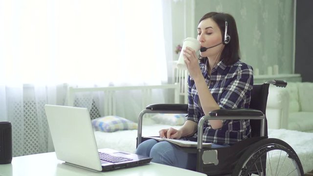 portrait young woman disabled, wheelchair, remote work at home, computer headset