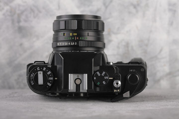 Old 35 mm SLR camera on a gray cement background.