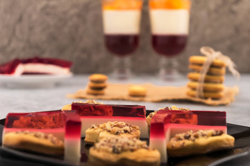 Obraz na płótnie Canvas Culinary decoration for Valentine's Day. Transparent jelly on a black plate. Homemade cookies with nuts. Glasses with a cocktail and fruit.