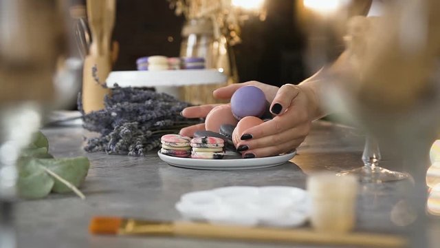 Female chef putting macaroons into the plate.
