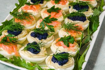 Stuffed eggs with salmon and caviar decorated by parsley and dill. Party food
