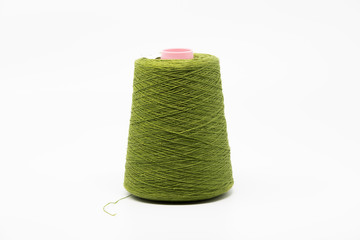 Dark green yarn thread used for weaving and sewing, isolated on white background.
