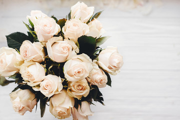 White roses bouquet on white wooden background isolated. Top view with space for text. Floral greeting card mockup. Wedding invitation,happy mother day or Valentine day concept