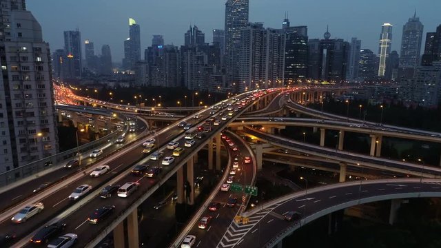 Tilting drone shot of spectacular elevated highway at night time, traffic drives over busy intersection during evening rush hour in Shanghai, transportation and infrastructure China