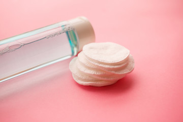 bottle with tonic or micellar cleansing water with fresh herbs and flowers and cotton pads on pink...