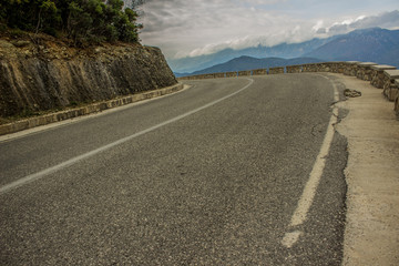 empty old curved asphalt car road way in mountain nature scenic landscape in cloudy autumn season time, infrastructure transportation concept