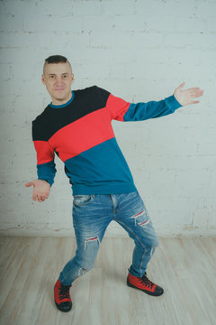 Emotional portrait of a guy in full height, crazy guy posing for the camera. Short hair, clean skin. Street style clothing sweatshirt and jeans. The concept of good mood. Model grimaces