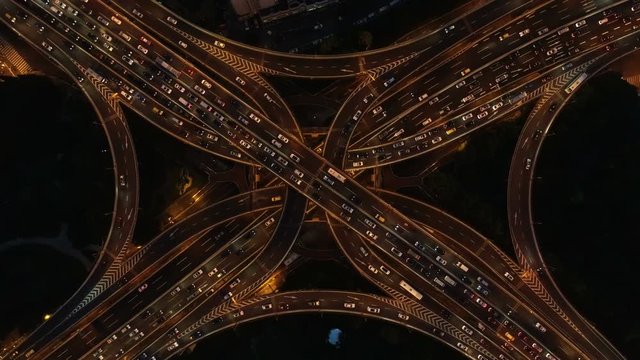 Overhead drone shot of traffic driving over busy interchange at night in Shanghai, air pollution and transportation in China