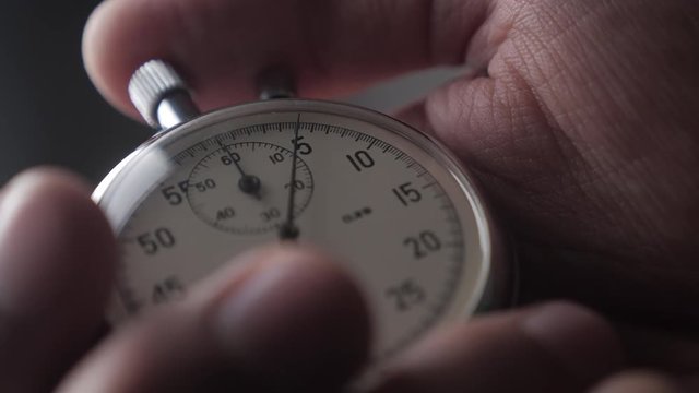 Close-up of one person starting up a stopwatch at grey background. 4K, 10 BIT, 4:2:2.