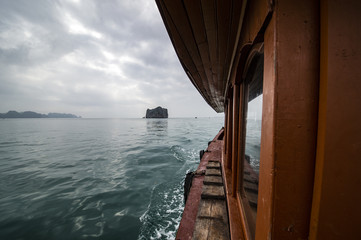 A tourists boat is sailing on the water of Ha long Bay in Vietnam. Ha Long Bay, in northeast Vietnam, is known for its emerald waters and thousands of towering limestone islands topped by rainforests.