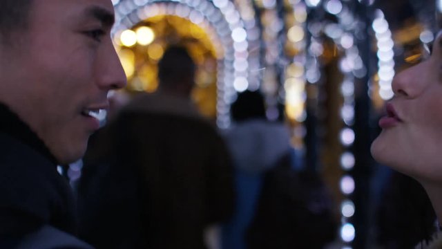 Camera follows a young couple walking and sharing a kiss