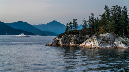 Sunset over Whyte Cliff, withs ferry leaving the terminal in the background. West Vancouver,...
