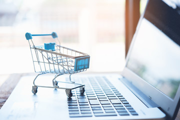 Online shopping concept. Shopping cart with laptop on the desk.