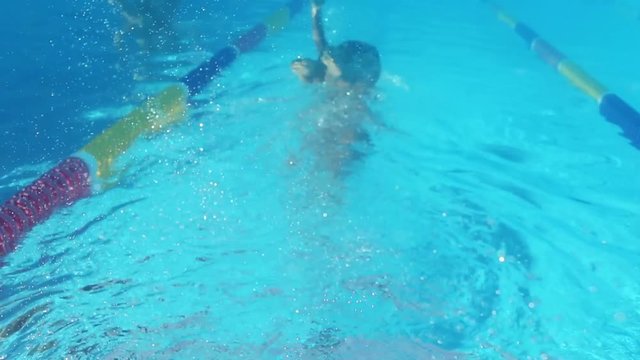 Woman is swimming underwater in pool during triathlon training