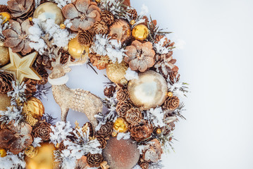 Top view Beautiful hand made golden Christmas wreath decorated with pine cones, ornamentals, spruce branches, balls, stars and decorative deer on white background isolated, flat lay. Copy space.
