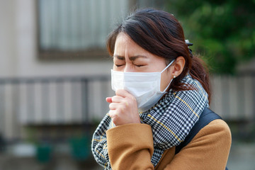 辛そうな表情しているマスクの女性