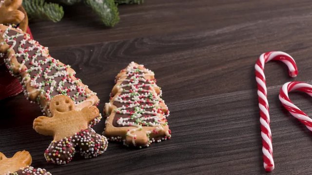 Christmas holiday background with gingerbread cookies, candy canes and evergreens over wooden table. Christmas and New year food. Christmas decoration and sweets on wood background.