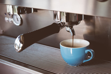 Espresso machine making coffee with blue cup in pub, bar, restaurant