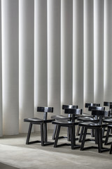 Many black wooden chairs on the background of the luminous white columns