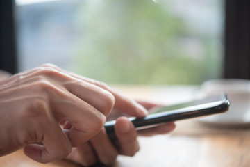 Men's hands are using a smartphone at home.