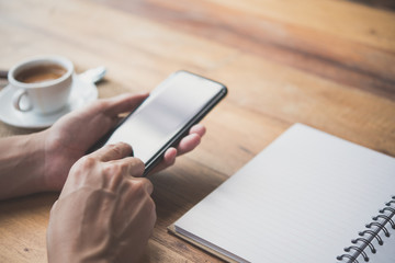 Men's hands are using a smartphone at home.